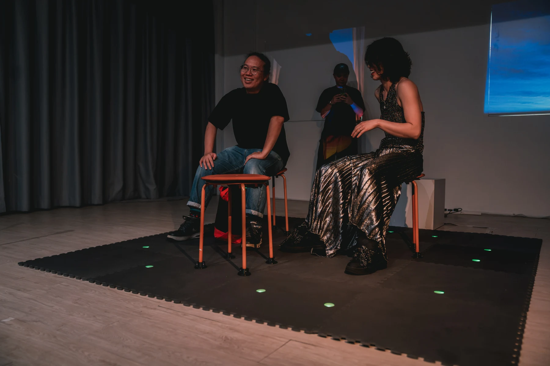 People sit among the stools and talk in the installation space.